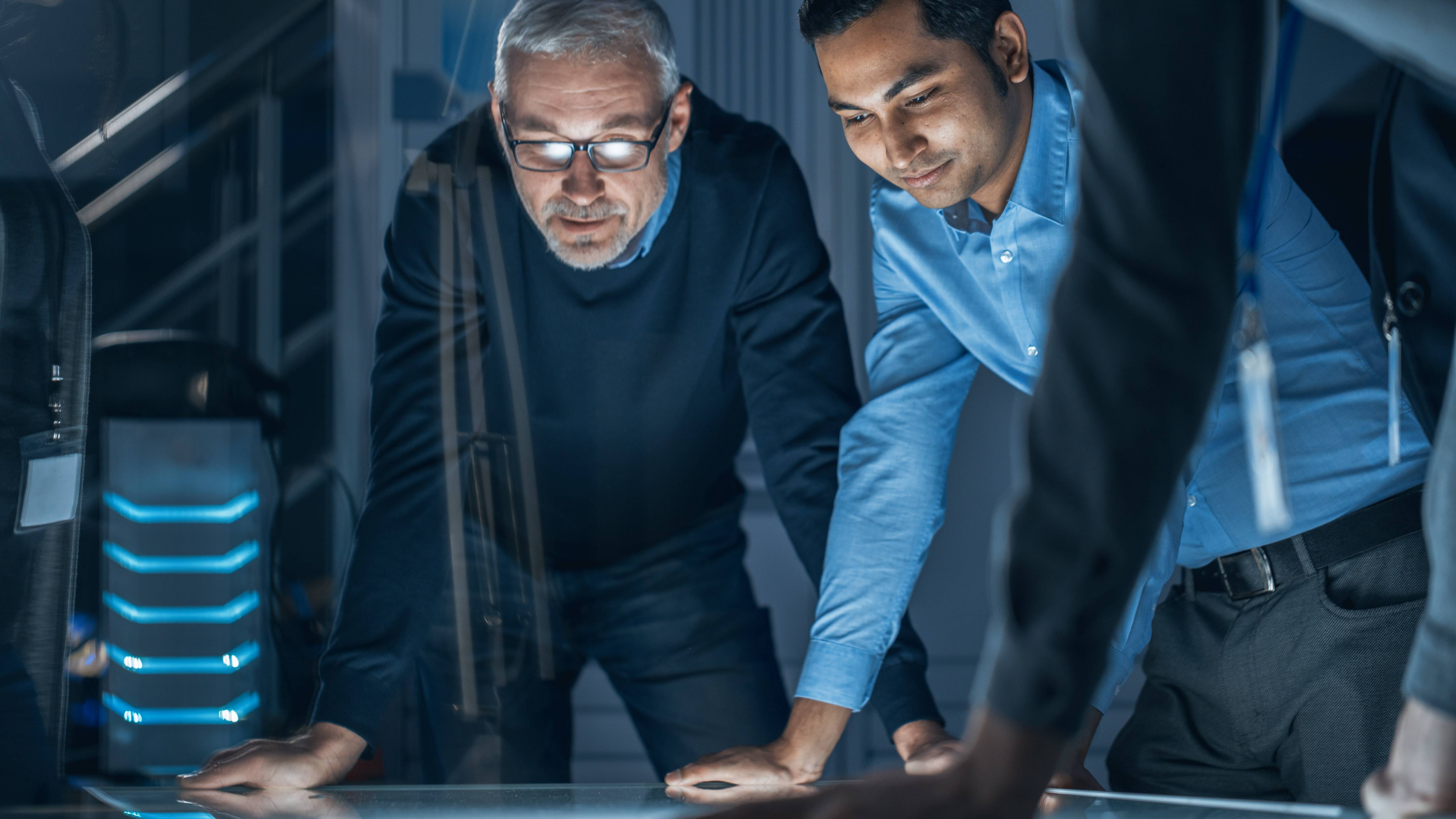 Two engineers leaning over an illuminated table in a technology lab