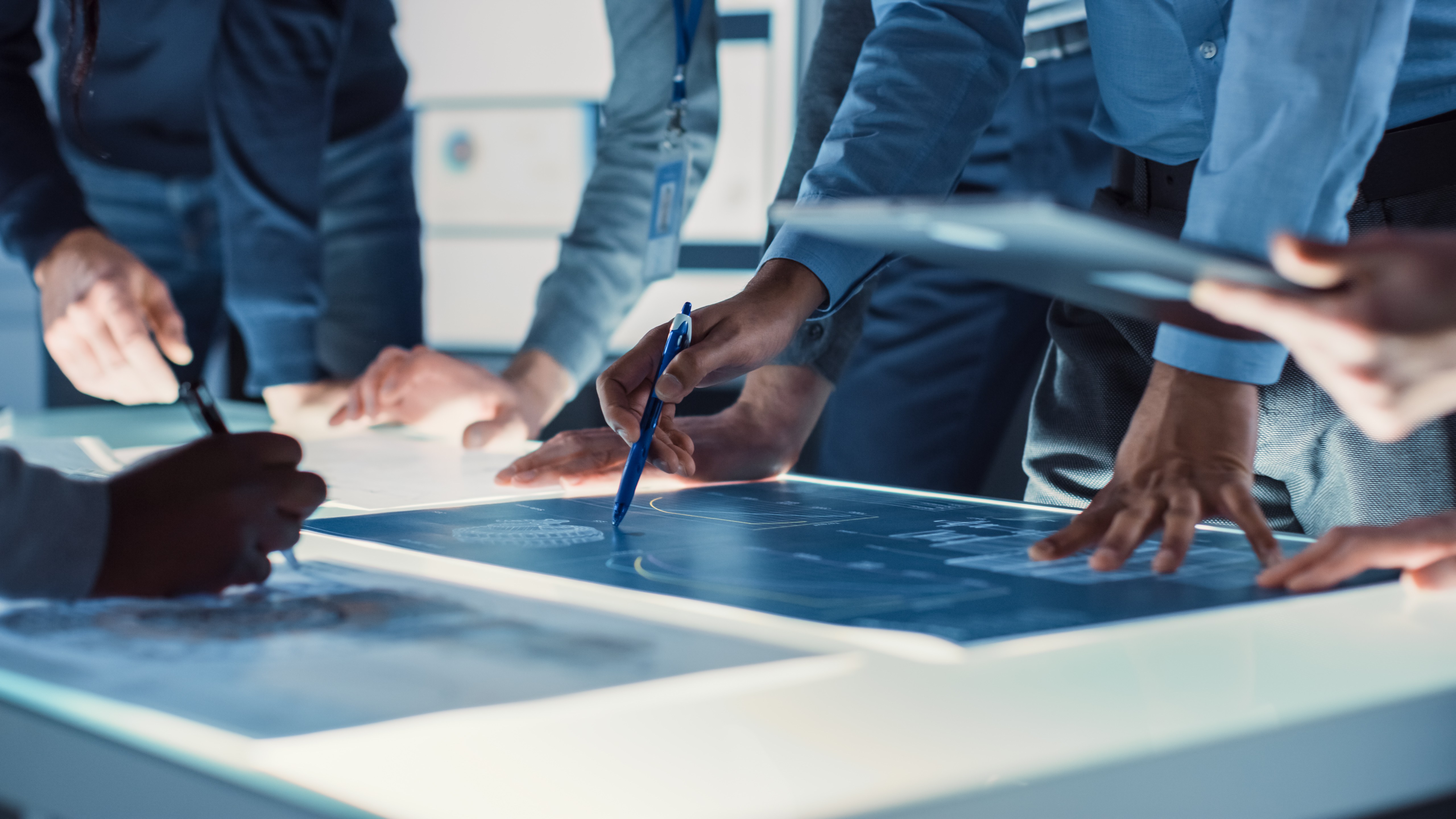 Engineers reviewing blueprints on an illuminated table